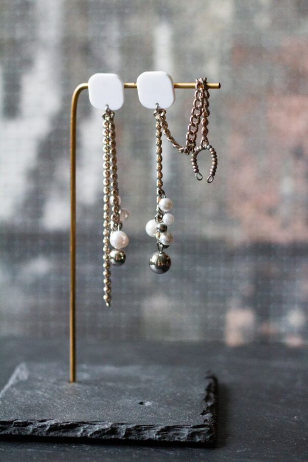 Ohrringpaar Weißer Stecker, Metallketten, unten Perlen aus Kunststoff. Ein Ohrring mit Earcuff