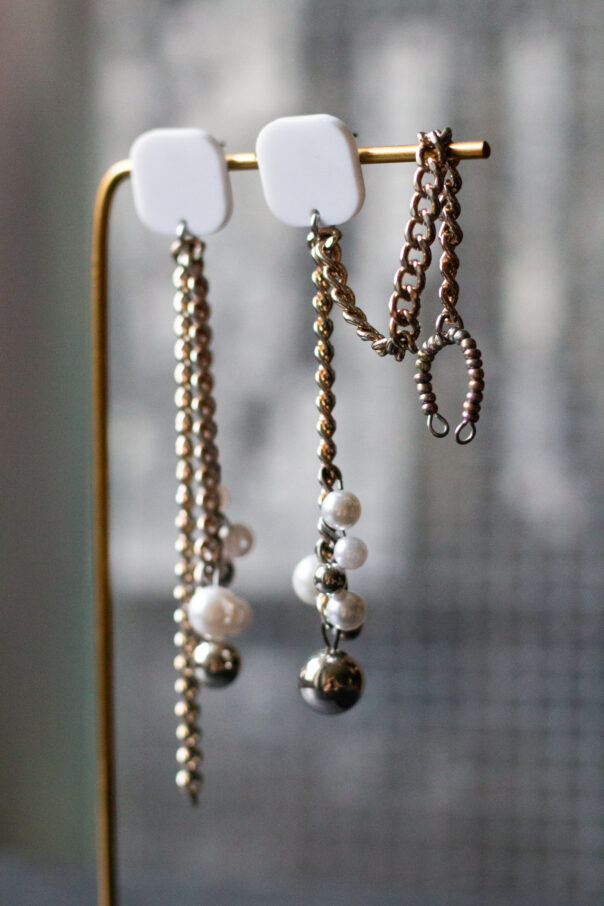 Ohrringpaar Weißer Stecker, Metallketten, unten Perlen aus Kunststoff. Ein Ohrring mit Earcuff