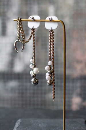 Ohrringpaar Weißer Stecker, Metallketten, unten Perlen aus Kunststoff. Ein Ohrring mit Earcuff