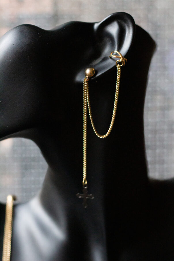 Detailaufnahme schwarze Büste mit Ohrring gold lange Kette und earcuff unten ein Kreuz
