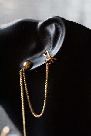 Detailaufnahme schwarze Büste mit Ohrring gold lange Kette und earcuff unten ein Kreuz