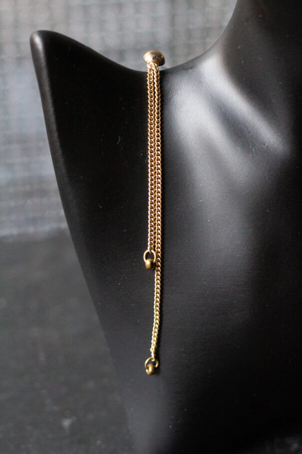 Detailaufnahme schwarze Büste mit Ohrring gold lange Kette und earcuff unten ein Kreuz
