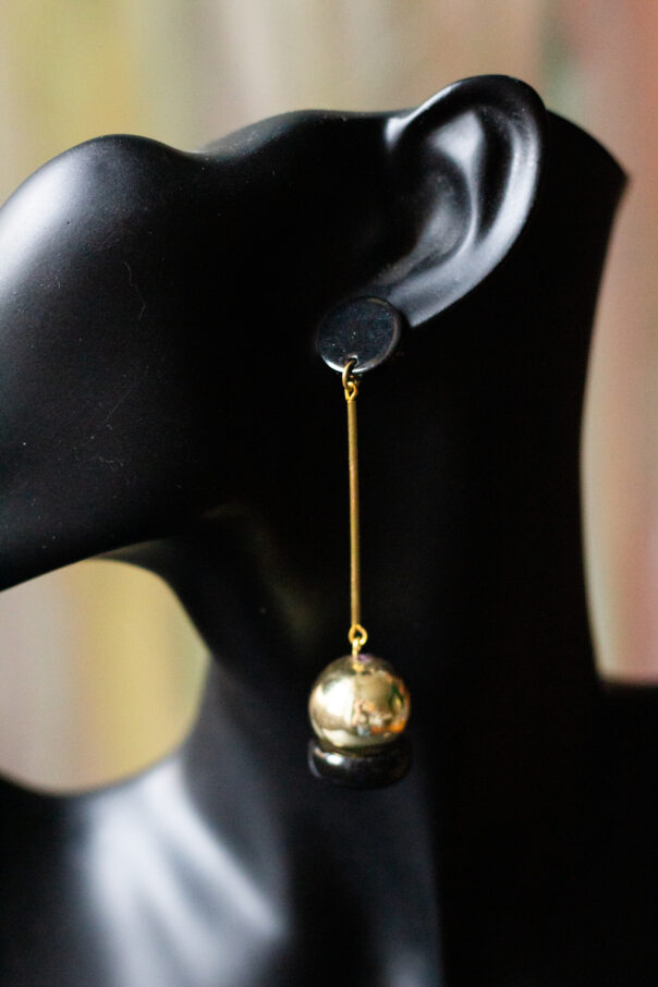 schwarze Büste mit Ohrring schwarzer Stecker, Messingrohr, goldene Kugel am Ende