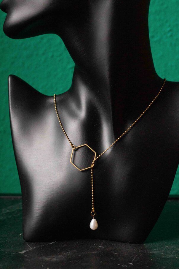 Detailaufnahme schwarze Büste mit Messing Wickelkette. 6 eckiges Mittelstück und Perle am Ende